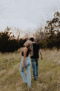 a man and woman are walking through the grass