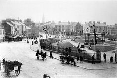 an old black and white photo of horse drawn carriages on a street with buildings in the background