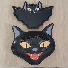 two black cat shaped plates sitting on top of a wooden table