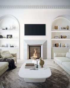 a living room with white furniture and a fire place in the middle of the room