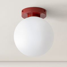 a white light hanging from the ceiling in a room with a red trim around it