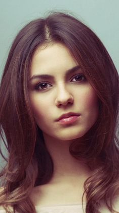 a woman with long brown hair is looking at the camera