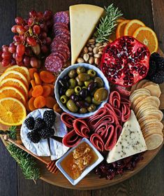 a wooden platter filled with different types of cheeses and fruit on top of it