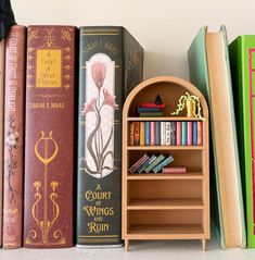 several books are lined up next to each other on a shelf in front of a white wall