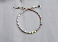 a white beaded bracelet with a smiley face charm and multicolored glass beads