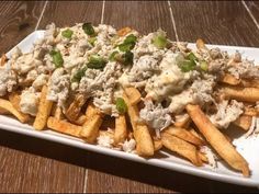 a white plate topped with french fries covered in chicken salad