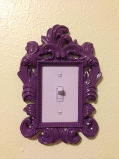 an ornate purple light switch cover hangs on the wall