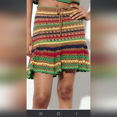 a woman wearing a multicolored crochet skirt and crop top with her hands on her hips