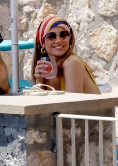 a woman sitting at a table with a drink in her hand