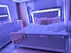 a bedroom with a bed, dresser and mirror in the corner is lit up by purple lighting