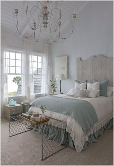 a bed room with a neatly made bed and a chandelier hanging from the ceiling