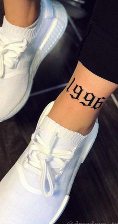 a person with a small tattoo on their ankle that reads,'999 '