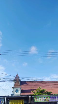 a clock tower on top of a building next to power lines and telephone wires in the sky