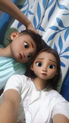 two dolls laying on top of each other in front of a blue and white curtain