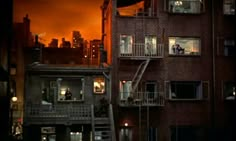 an apartment building at night with fire in the sky and people standing on the balconies