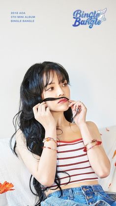 a woman sitting on top of a white couch holding a cell phone to her ear