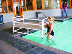 a woman in a bathing suit standing next to a swimming pool with steps leading up to it