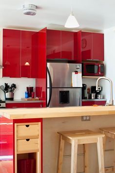 a kitchen with red cabinets and two stools