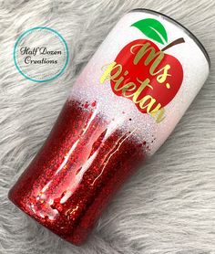 a red glitter tumbler with an apple on it