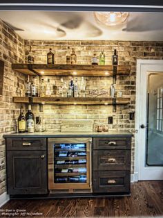 a brick wall with shelves and bottles on the top, behind it is a wine cooler