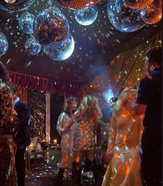 several people are dancing on the dance floor with disco balls hanging from the ceiling above them