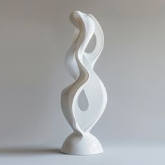 a tall white sculpture sitting on top of a table next to a gray wall and floor