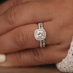 a woman's hand with a diamond ring on top of her finger and the other hand holding an engagement ring