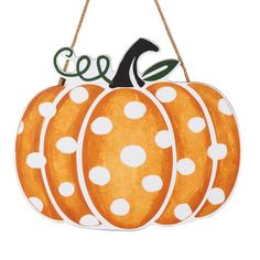 an orange and white pumpkin hanging from a rope with polka dot print on it's side