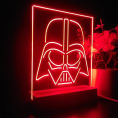 a darth vader light up box with flowers in the background and a potted plant behind it