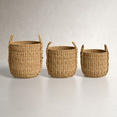 three woven baskets sitting next to each other on a white surface with no one in the photo