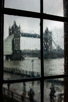 a window with the view of tower bridge and river thames in london, england on a rainy day