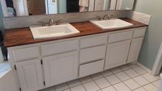 two white sinks sitting under a mirror in a bathroom