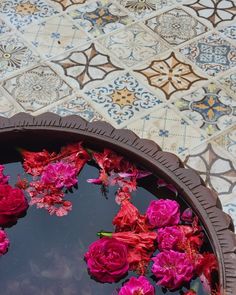 pink flowers floating in a bowl of water on a mosaic tile flooring patterned area