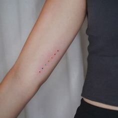 a woman's arm with colorful dots on it and a black shirt behind her