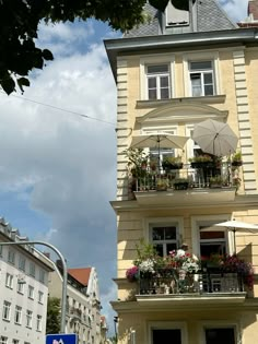 an apartment building with balconies and flowers on the balcony, next to a street sign