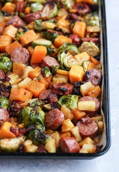 a casserole dish with sausage, brussel sprouts and sweet potatoes