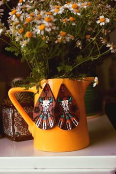 a yellow pitcher filled with flowers on top of a table