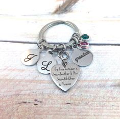 two heart shaped key chains with charms attached to them on top of a wooden table