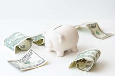 a piggy bank with money coming out of it on a white surface, in the foreground