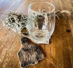 a glass with some plants in it on a wooden table