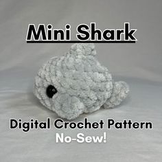 a small white stuffed animal sitting on top of a white background with the words, mini shark digital crochet pattern no sew