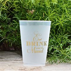 a plastic cup sitting on top of a table next to some plants and bushes in the background