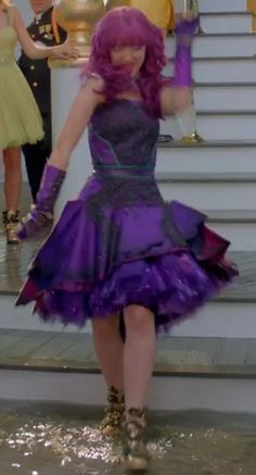 a woman in a purple dress is walking down the stairs with other people behind her