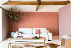 a living room with pink walls and white furniture