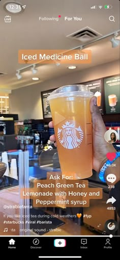 someone is holding up a cup of iced medicine ball tea in front of a restaurant