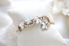 Intricate & stunning, our floral Wedding Bracelet is designed to resemble a dainty floral vine with ornate metal leaves with white opal crystals. - Handcrafted with genuine Austrian crystals. - Each stone is set by hand in my studio - White opal crystals - Antique gold finish - Bracelet measures 6 inches and extends to 8 inches - Handcrafted in the US. - Nickel free and hypoallergenic - READY TO SHIP AS PICTURED IN ANTIQUE GOLD, OTHERWISE PLEASE ALLOW APPROX 10 BUSINESS DAYS FOR COMPLETION This Delicate White Bracelet For Wedding, Delicate Bangle Jewelry For Wedding, Adjustable Flower-shaped Jewelry For Weddings, White Bangle Bracelet For Wedding, Adjustable Flower-shaped Wedding Jewelry, Elegant Flower Jewelry For Marriage, Dainty Flower Jewelry For Wedding, Dainty Flower-shaped Wedding Jewelry, Dainty Flower Wedding Jewelry