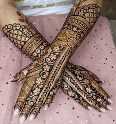 a woman's hands decorated with hennap and gold glitters on it