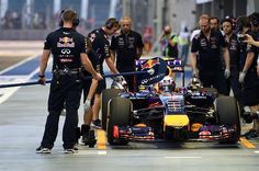 a red bull racing car being worked on by the team at the pit line with mechanics