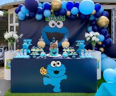 a sesame street birthday party with blue and gold balloons, cookie monster decorations, and desserts