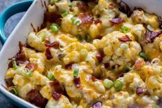 a casserole dish with bacon, cheese and green onions